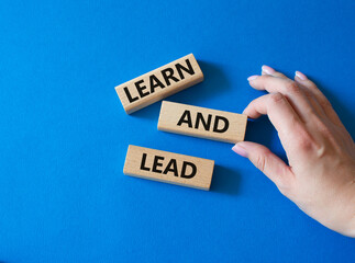 Learn and lead symbol. Concept words Learn and lead on wooden blocks. Beautiful blue background. Businessman hand. Business and Learn and lead concept. Copy space.