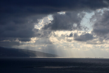 the sun rays shine through the clouds on the sea surface