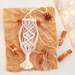 Christmas macrame toys on craft papper. White background. Natural materials - cotton thread, wood beads and stick. Eco decorations, ornaments, hand made decor. Winter and New Year holidays