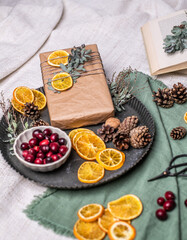 Geschenke weihnachtlich verpacken, Natürliche Geschenkverpackung zu Weihnachten mit Cranberrys, Zapfen und Orangenscheiben in Backpapier