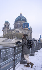 Young female tourist leaning against the river and cathedral in Berlin, Germany.