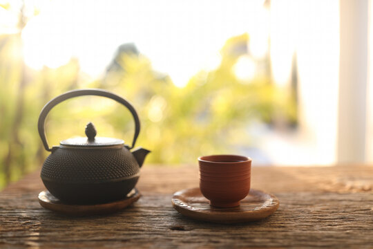 Tea cup and black metal tea pot on wooden table