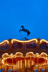 horse on the top of roundabout, galloper. Children's Carousel close up in the night illumination. Outdoor vintage colorful luminous. Retro Shiny Carousel details, horses. vertical photo, bottom view