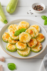 Baked zucchini with cheese, garlic and fresh herbs on a white wooden background. Selective focus