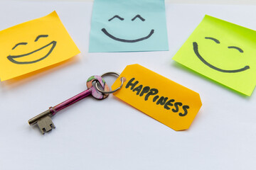 A key to happiness concept with a key and hand drawn happy faces isolated in a white background.