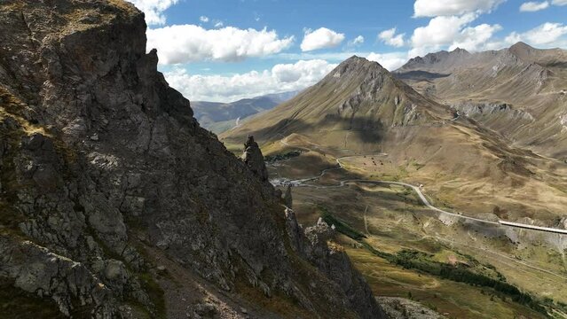 Close aerial shot along rocky peaks discovering a valley with glacier in background french alps