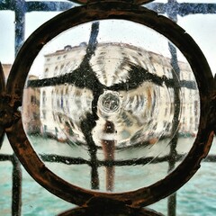 Closeup shot of a thick round pane of glass distorting a view of Venice, Italy