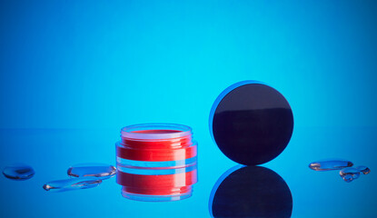Cosmetics tub with face blusher isolated on a cool blue background.