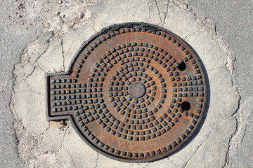 cast iron manhole on asphalt background.