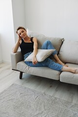 Fototapeta premium Young woman with short haircut hair having fun at home on the couch smile and happiness, vacation at home, natural posing without filters, free copy space