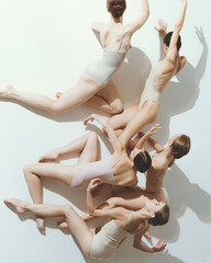 Group of young girls, ballet dancers performing, posing isolated over grey studio background. Chaotic. Top view
