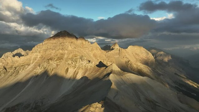 Sun lighting rocky summits in the french alps aerial high shot with clouds