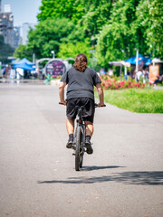 Rear view with a man in the park ridding a bicycle. Ciclyst in Youth Park (Tineretului) Bucharest, Romania.