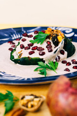 Close up of a chile en nogada, with pomegranate and cilantro. Food.