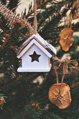 Vintage wooden toy house on Christmas tree. Natural Xmas ornaments for Christmas tree, zero waste, soft focus