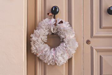 Christmas crown wreath of plastic bags on front door. DIY Xmas zero-waste ornaments. Christmas decoration