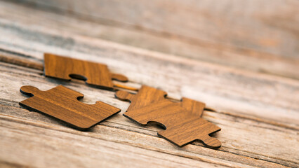 Brown pieces of puzzle stand on wooden table. Empty copy space for inscription or objects. idea, sign, symbol, concept of connecting