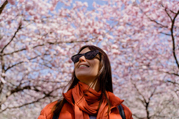 Spring. A woman walks in the park where the trees have blossomed with flowers.