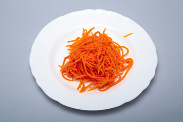 Thinly sliced carrots on a white plate on a gray background