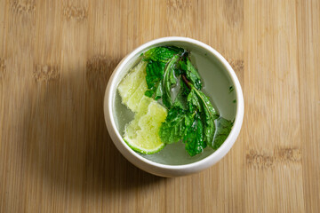 Mojito lime and mint in white mug isolated on wooden background