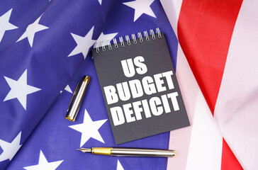 On the American flag lies a pen and a notebook with the inscription - US budget deficit