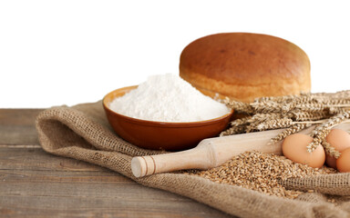 Wheat ears and flour on wooden background