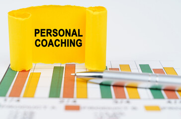 On the business charts are a pen and a paper plate with the inscription - PERSONAL COACHING