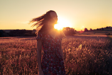 Gorgeous young woman in a wheat field on a sunset background.