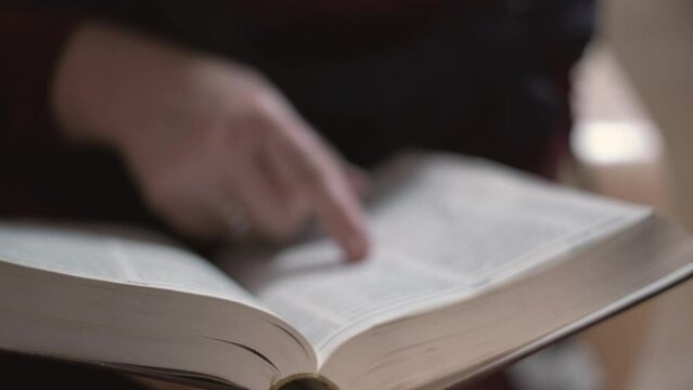 Woman in a dark room flipping through a book or dictionary preparing for an exam