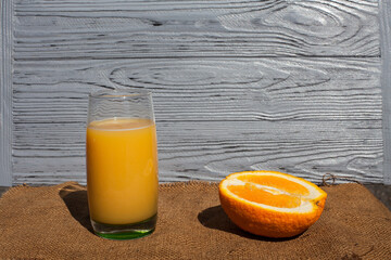 A composition of fresh fruit and drink. Orange lying around an orange juice in a glass, on a dark...