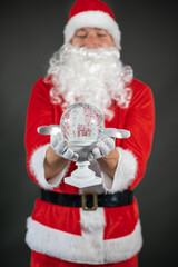
Portrait von einem verkleideten Weihnachtsmann mit einem Geschenk in der Hand vor grauen Hintergrund 