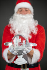 
Portrait von einem verkleideten Weihnachtsmann mit einer Schneekugel in der Hand vor grauen...