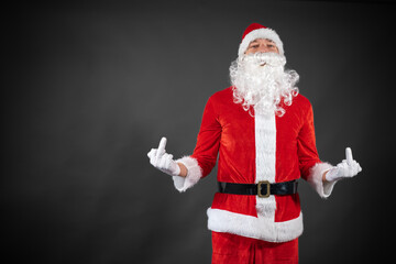 
Portrait vom Weihnachtsmann der auf einen Platzhalter zeigt und isoliert vor grauen Hintergrund...