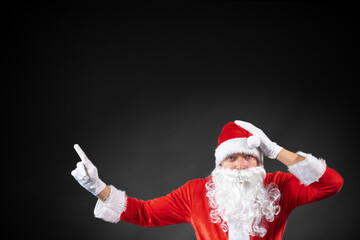 Fototapeta na wymiar Portrait vom Weihnachtsmann der auf einen Platzhalter zeigt und isoliert vor grauen Hintergrund ist 
