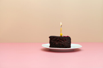 chocolate slice cake with candle on pink background-happy birthday tart -minimalistic image - obrazy, fototapety, plakaty