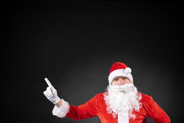 
Portrait von einem verkleideten Weihnachtsmann der auf einen Platzhalter zeigt und isoliert vor grauen Hintergrund ist 