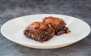 Chocolate baklava on a white plate. Turkish style chocolate baklava presentation and service. Horizontal view.