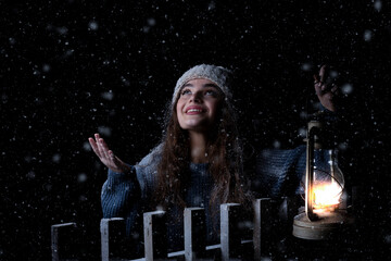 A girl illuminates her way on the snow with a lamp. Studio photo.