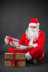 
Portrait von einem verkleideten Weihnachtsmann mit einem Geschenk in der Hand vor grauen...