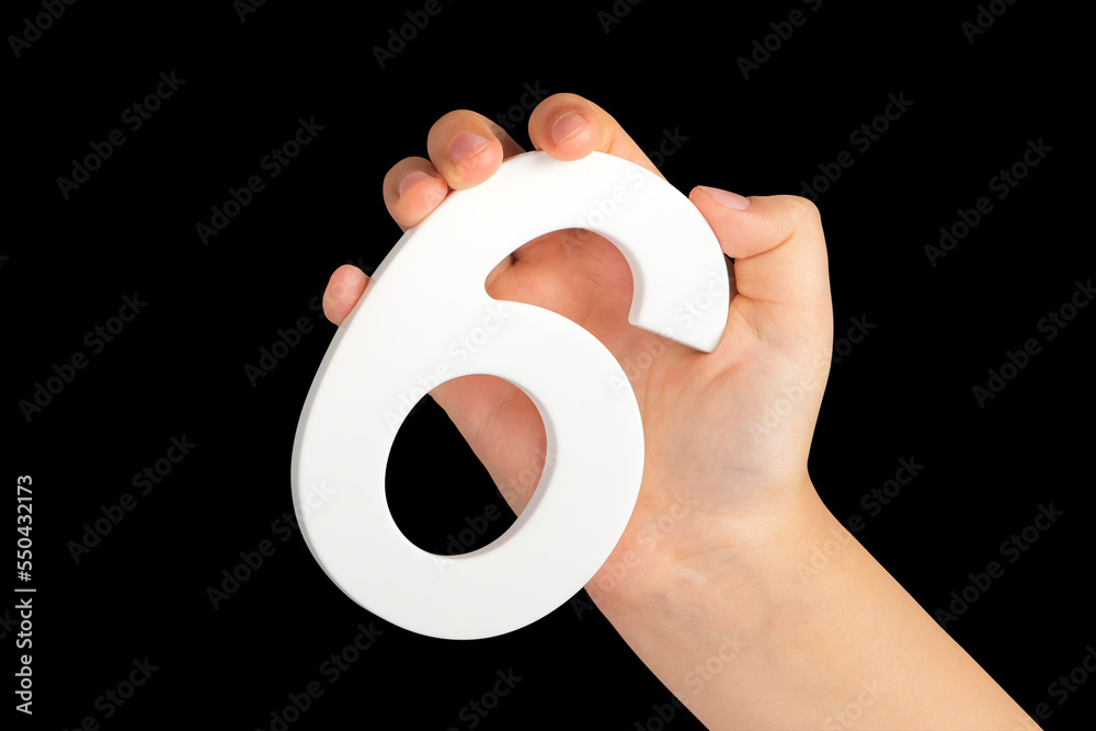 Poster number six in hand isolated on black background. number six in a child's hand holding on a black bac