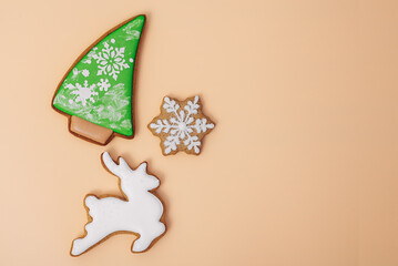 Christmas holiday background with gingerbread cookie of white deer shaped, christmas tree and snowflake on color background, top view, space for text. Happy new year and merry christmas concept
