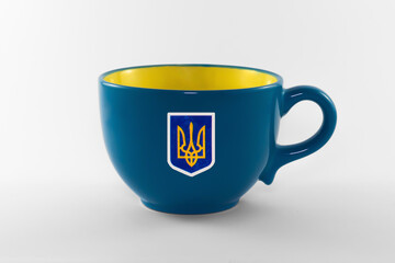 Empty decorative yellow and blue cup isolated on white background. The cup has a patriotic sticker of Ukraine