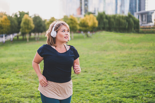 young plus size woman running in a city park, healthy and fitness lifestyle, body positive concept