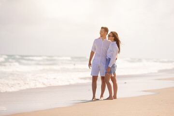Fototapeta na wymiar Young couple in love on the beach summer vacation. Happy man and woman look at the sea 