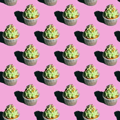 Creative seamless pattern made of Christmas baubles with sprinkles and ribbons on a pastel pink...