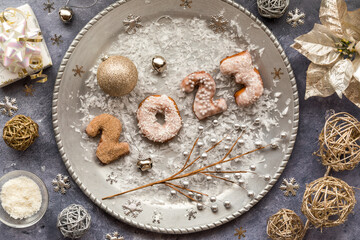 New Years donuts for 2023 on a silver tray surrounded by festive decorations.