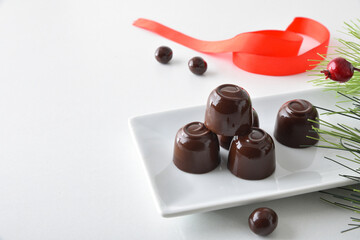 Chocolate candies on plate on white and red bow