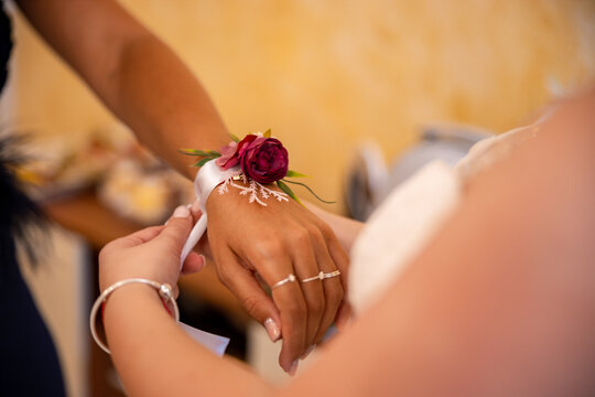 Bride places a flower corsage on the hand of her maid of honor. High quality photo