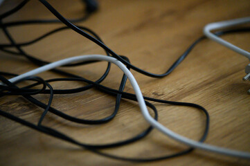 Cable chaos clutter from multiple electric wire extension cords and multi-contact plugs on wooden...