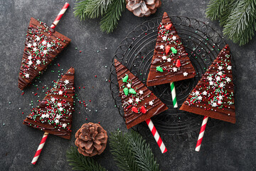 Chocolate brownies Christmas tree with chocolate icing and festive sprinkles on stone table....